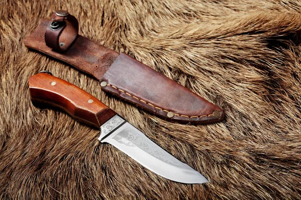 hunting knife with leather sheath on a wild boar furs background