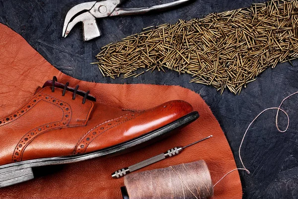 Moda klasik erkek kahverengi oxford brogues deri ve ayakkabı çivileri formunda, koyu ahşap masa ayakkabıcı araçlarıyla emretti parçası üzerinde cilalı. Üstten Görünüm. Kavram ayakkabı için yaratıcı