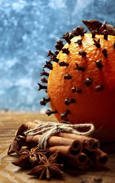 Рождественские апельсины с гвоздикой и коричневыми палочками крупным планом против замороженных окон — стоковое фото