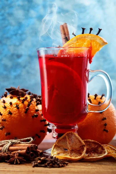 Glass of christmas hot mulled wine on wooden table with species and oranges against frozen window.Closeup — Stock Photo, Image
