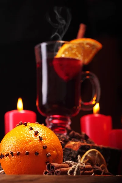 Glass of christmas hot mulled wine on wooden table with species ,oranges and red candles against black background.Closeup.Slective focus — Stock Photo, Image