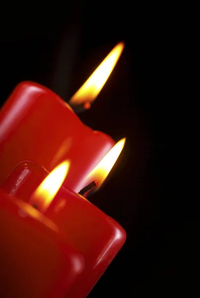 Primo piano di tre candele rosse accese contro sfondo nero. Primo piano. Copia spazio — Foto Stock