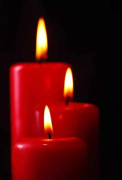 Closeup of three red burning candles against black background .Closeup .Copy space — Stock Photo, Image