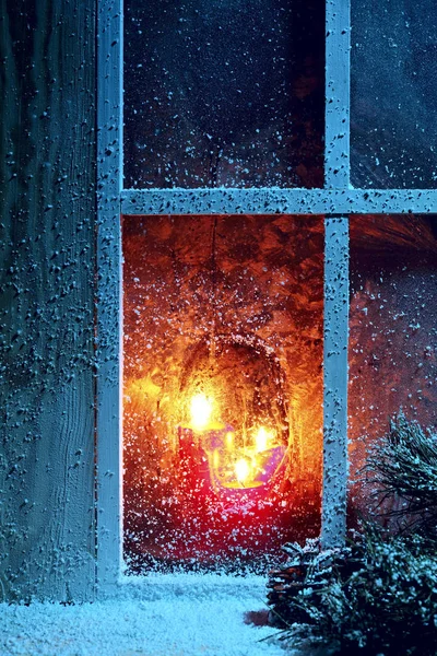 Frosted window with burning candles.Christmas greeting card.Athmosperic photography.Closeup. Selective focus.Christmas night