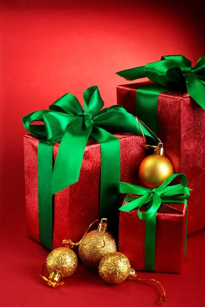 Red gift boxes with green ribbons and bow with golden Christmas balls on red holiday background . Merry christmas card. Winter xmas theme.Boxing day — Stock Photo, Image