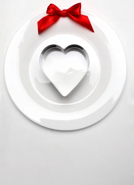 Formy metalowe serca na białe płytki z czerwoną wstążką łuku. Tło na Walentynki. Przestrzeń Minimalism.Copy — Zdjęcie stockowe