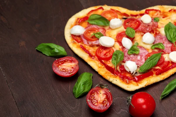 Rajčata a Pizza ve tvaru srdce s salám, bazalkou a mozzarellou tmavé dřevěné hnědé pozadí. Kopírovat prostoru. Pohled shora. Creative valentine den pozadí. Pojetí lásky. Closeup.Selective zaměření — Stock fotografie