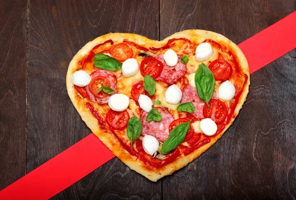 Restaurace Pizza ve tvaru srdce s salámem, rajčaty, bazalkou a mozzarelou tmavé dřevěné hnědé pozadí. Kopírovat prostoru. Pohled shora. Creative valentine den pozadí. Láska koncept — Stock fotografie