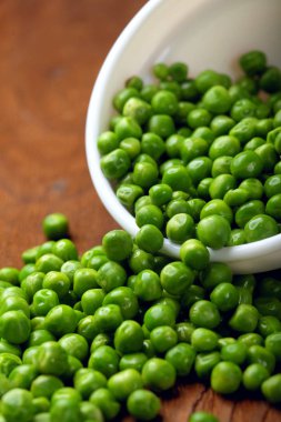 Yeşil bezelye. Beyaz kase. Ahşap arka plan üzerinde masa. Uzay kopyalayın. Seçici odak. Portre