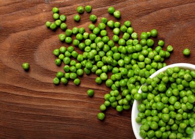 Yeşil bezelye. Beyaz kase. Ahşap arka plan üzerinde masa. Üstten Görünüm. Kopya alanı