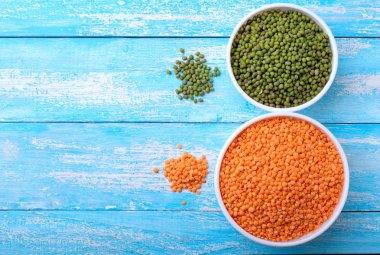 Kırmızı mercimek ve yeşil fasulye veya mavi ahşap bir masa üzerinde bir kapta mung fasulye. Uzay kopyalayın. Üstten Görünüm