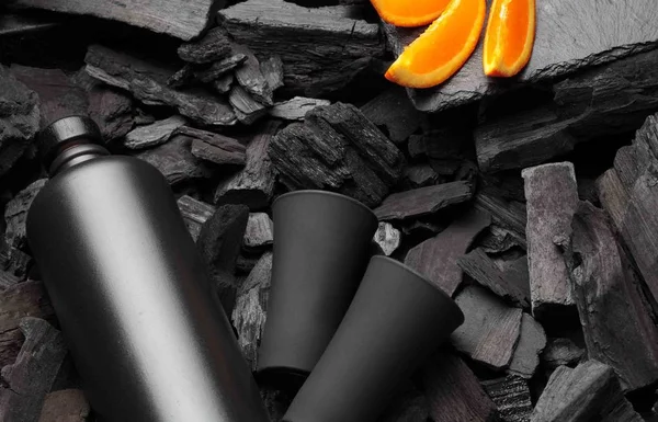 Original black matte bottle of vodka or tequila and shot glass .Slices of oranges.On charcoal background. Black edition.Creative.Let's drink.Cheers.Copy space