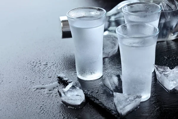 Vodka. Tiros, copos com vodka com gelo .Dark pedra background.Copy espaço .Selective foco — Fotografia de Stock