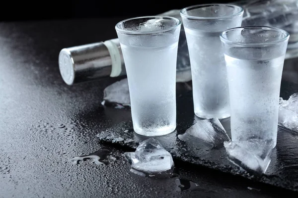 Vodka. Shots, glasses with vodka with ice .Dark stone background.Copy space .Selective focus — Stock Photo, Image