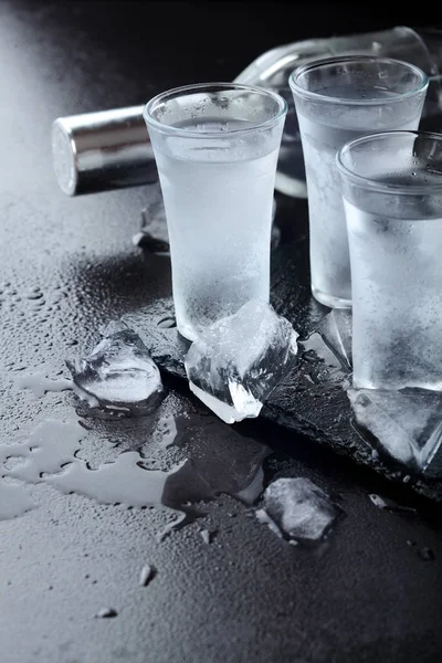 Vodka. Shots, glasses with vodka with ice .Dark stone background.Copy space .Selective focus