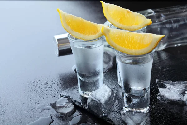 Wodka. Schoten, glazen met wodka en citroen met ijs. Donkere stenen achtergrond. Kopieer ruimte. Selectieve aandacht — Stockfoto