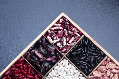 Bakliyat fasulye farklı türleri. Ahşap kutusunda. Fasulye çeşitleri. Üstten Görünüm. Closeup.Texture.Copy alanı. Karanlık taş arka plan üzerinde