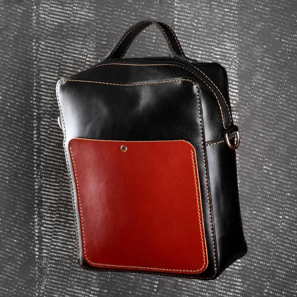 Messenger bag .leather black and red handmade bag on gray background.