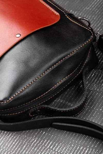 Messenger bag .leather black and red handmade bag on gray background.Closeup