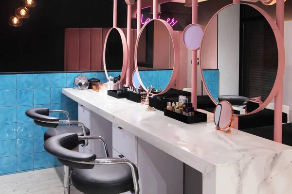 Інтер'єр розкішного стильного салону краси. стільці та стіл з косметикою для макіяжу. Рожевий концепт дизайну . — стокове фото