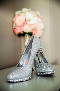 Bir buket önünde güzel parlak ayakkabıları duran. Arayanların gümüş ayakkabı. Düğün ayakkabıları gelin stilettos değerli taşlarla süslenmiş.