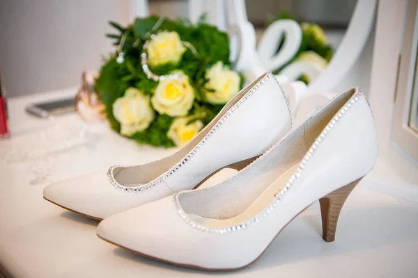 Beautiful wedding shoes stand on a table next to the mirror. White wedding shoes bride. bride stilettos.