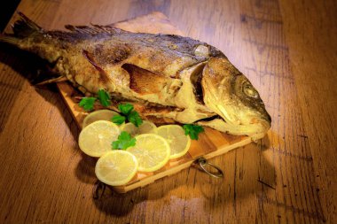 Güzel, parlak bir balık pişmiş. Kocaman bir altın balık. Limon ve maydanozla pişirilmiş büyük bir sazan balığı..