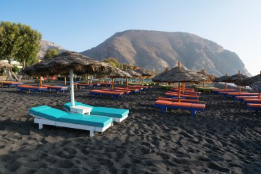 Perissa sahilinde bronzlaşma yatakları ve şemsiyeler, Santorini, Yunanistan