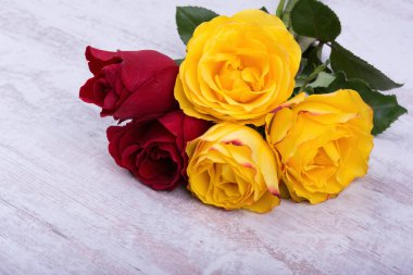 Beyaz ahşap zemin üzerinde kırmızı ve sarı güller