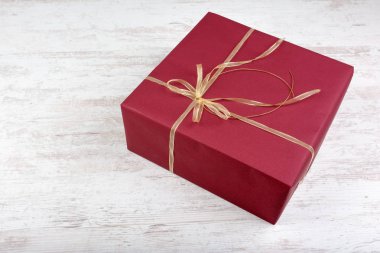 Beyaz ahşap zemin üzerinde altın şerit ile kırmızı hediye kutusu