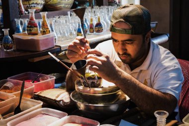 Dubai, Birleşik Arap Emirlikleri - 7 Aralık 2016: Usta Hatıra Eşyası renkli kum kullanarak bir şişeye yapar..