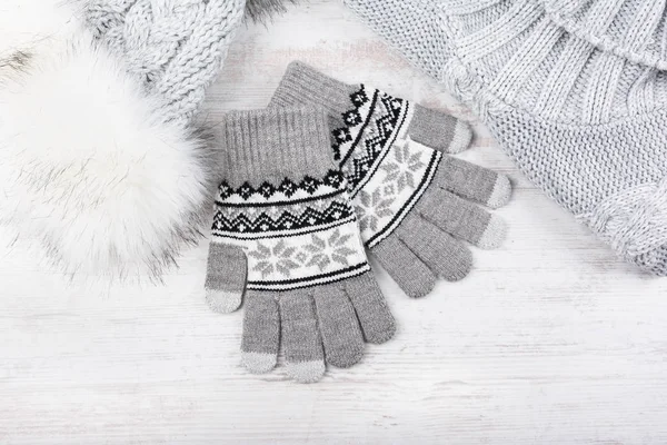 Winter-Strickhandschuhe, Pelzmütze und Pullover auf weißem Holzgrund. Set graue Strickkleidung. — Stockfoto