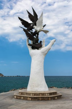 Kuşadası, Türkiye - 20 Ağustos 2017: Barış heykel Kuşadası, Türkiye'de sahildeki güvercinler ile el.