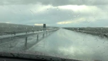 Arabanın ön camına yağmur damlıyor. Araba camından yağmurlu bir gün manzarası. Yağmurlu sezon konsepti.