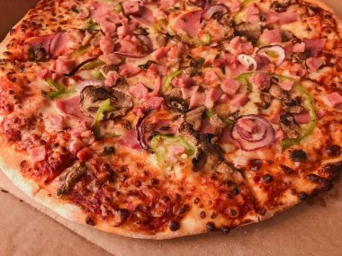 Pizza jambon, pastırma, domates, mantar soğan ve biber ile. Pizza teslim karton kutu içinde.
