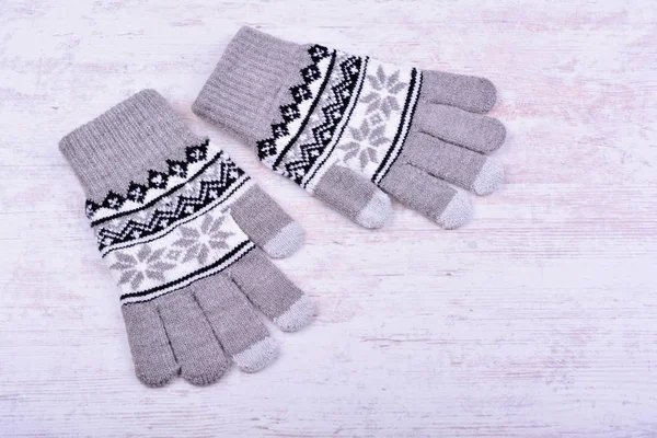 Ein Paar gestrickte Winterhandschuhe auf weißem Holzhintergrund — Stockfoto
