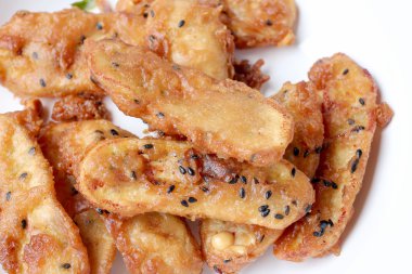 Kızarmış muz ahşap masa arka plan üzerinde beyaz tabak susam lezzetli geleneksel gıda serpilir. -Tay Snack