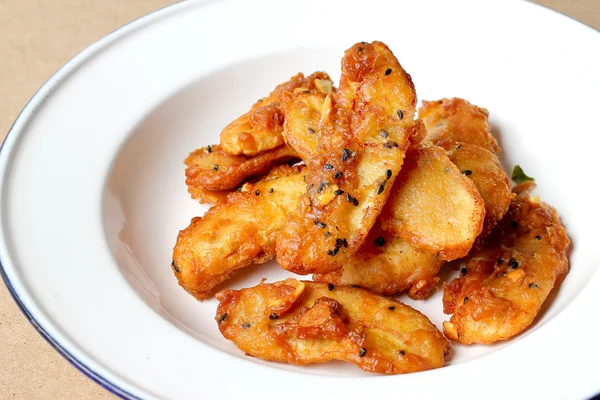 Bananes frites saupoudrées de sésame savoureux aliment traditionnel dans un plat blanc sur fond de table en bois. - Snack thaïlandais — Photo