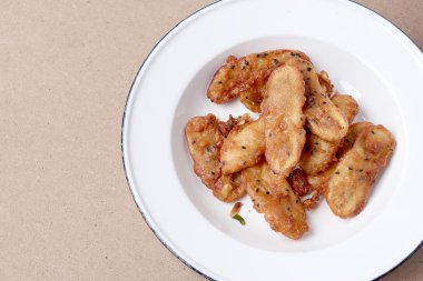 Kızarmış muz ahşap masa arka plan üzerinde beyaz tabak susam lezzetli geleneksel gıda serpilir. -Tay Snack