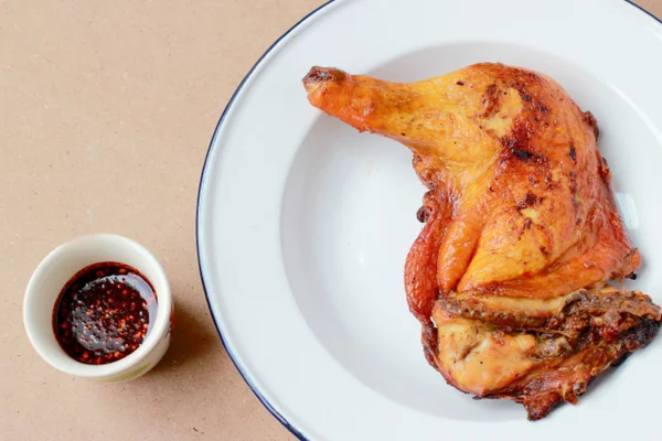 Patas de pollo a la parrilla en plato blanco con salsa picante en una taza pequeña sobre fondo de madera. Primer plano. vista horizontal desde arriba . —  Fotos de Stock