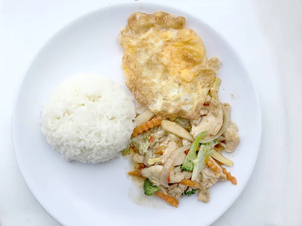 Aduk sayuran goreng dengan fillet ayam, goreng telur dengan nasi di piring putih di latar belakang putih . — Stok Foto