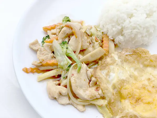 Aduk sayuran goreng dengan fillet ayam, goreng telur dengan nasi di piring putih di latar belakang putih . — Stok Foto