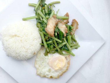 Biber ve soya sosu ve üzerinde beyaz tabak beyaz arka plan üzerinde Tayland gıda izole gevrek domuz kızarmış su ıspanak karıştırın.