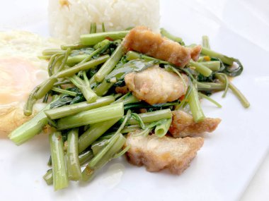 Biber ve soya sosu ve üzerinde beyaz tabak beyaz arka plan üzerinde Tayland gıda izole gevrek domuz kızarmış su ıspanak karıştırın.