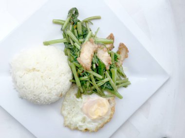 Biber ve soya sosu ve üzerinde beyaz tabak beyaz arka plan üzerinde Tayland gıda izole gevrek domuz kızarmış su ıspanak karıştırın.