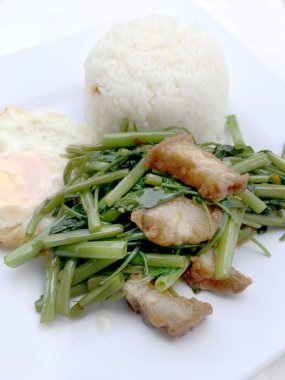 Biber ve soya sosu ve üzerinde beyaz tabak beyaz arka plan üzerinde Tayland gıda izole gevrek domuz kızarmış su ıspanak karıştırın.