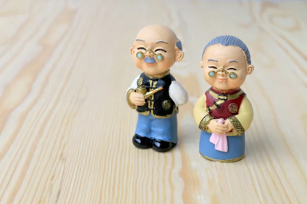 Grandma and grandpa dolls in chinese uniform style standing on wooden background. in chinese new year