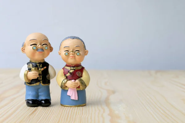 Grandma and grandpa dolls in chinese uniform style standing on wooden background. in chinese new year