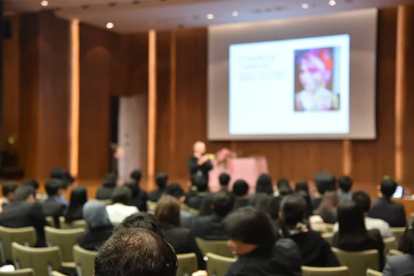 Blurred image of education people and business people sitting in conference room for profession seminar and the speaker is presenting new technology and idea sharing with the content activity.