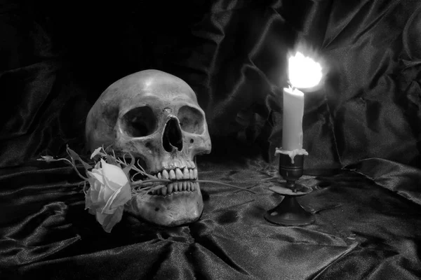 Crânio com Bando de flores e luz de vela na mesa de madeira com fundo preto na noite em preto e branco / estilo de vida morta — Fotografia de Stock